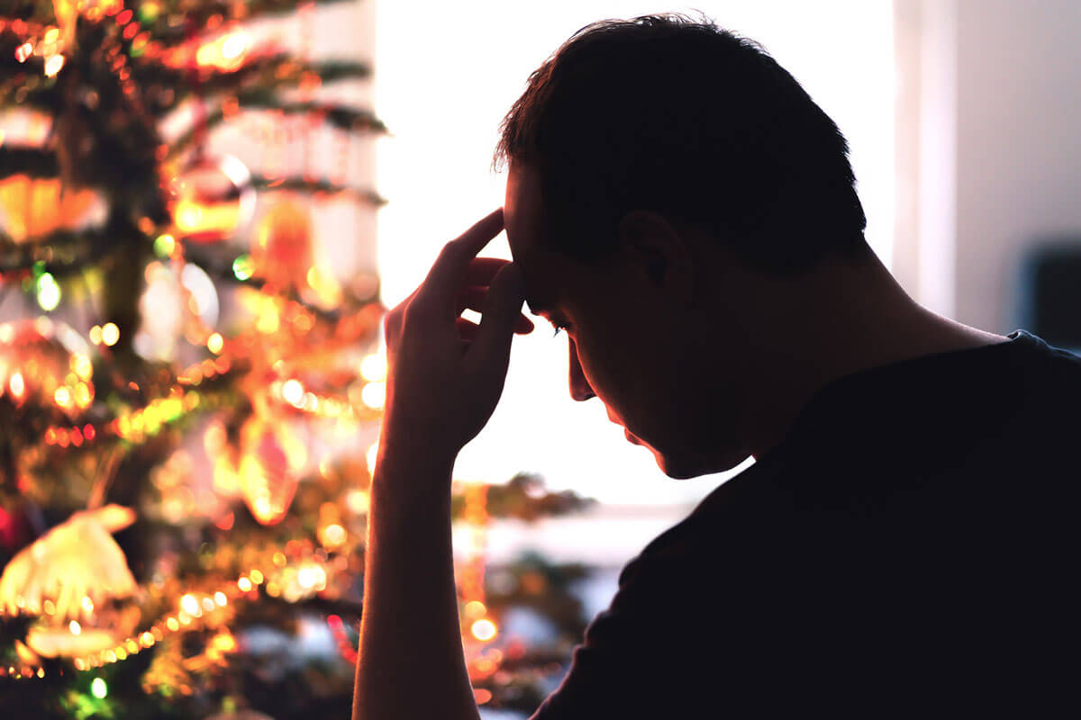 AdobeStock_473952553_WEB-2 Sad man sitting in front of a Christmas tree
