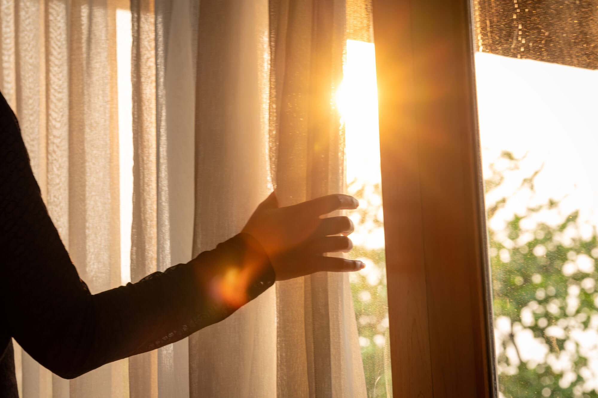 Gibson_Curtain_webjpg Hand pulling open curtains to reveal shining sun