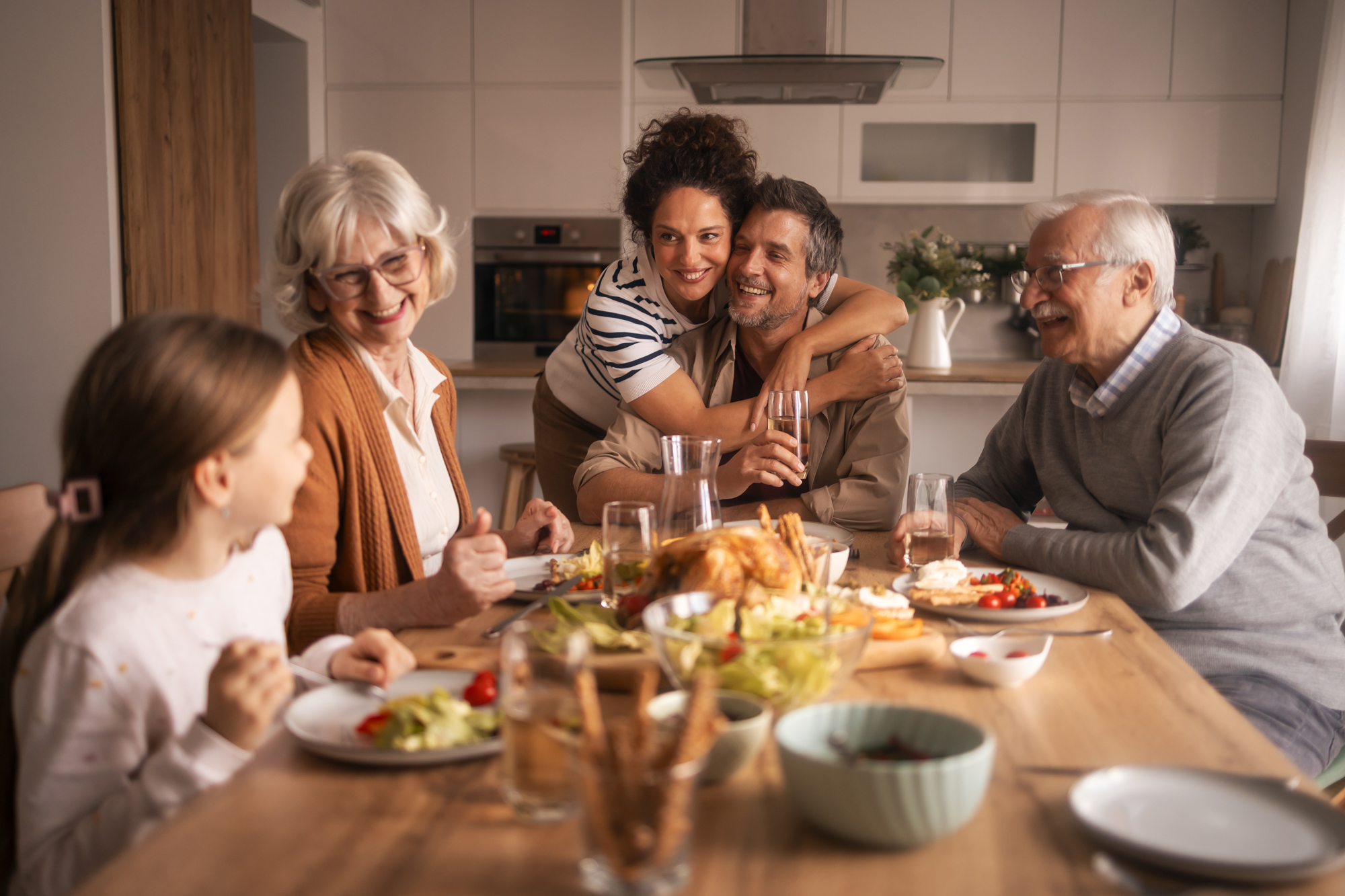 Multi-generational family embracing and laughing together at a shared holiday meal, representing connection and support within the family